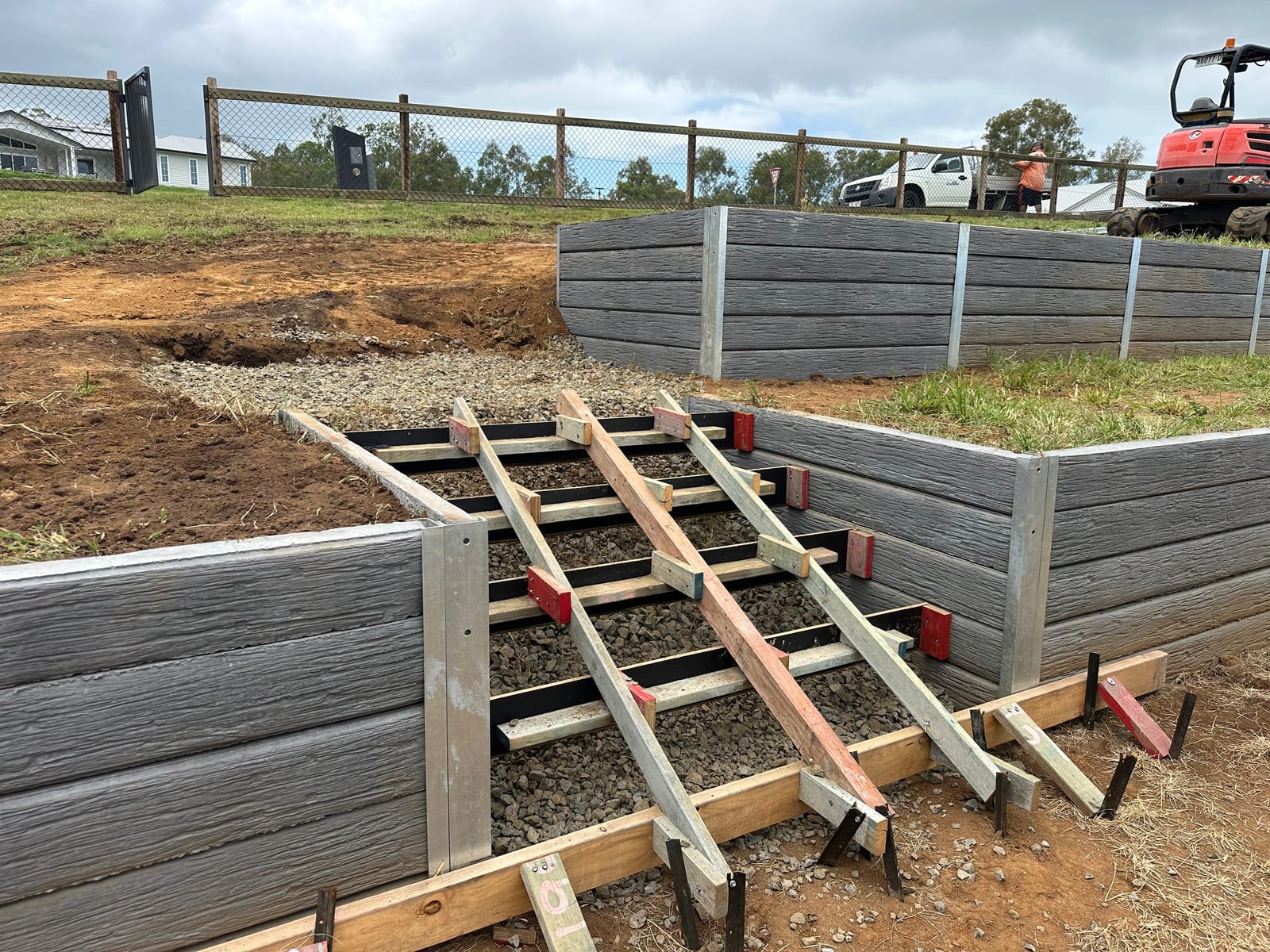 Concrete sleeper retaining wall with steel posts under construction